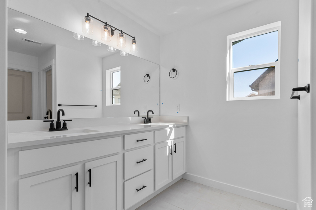 Full bath with baseboards, a sink, double vanity, and visible vents