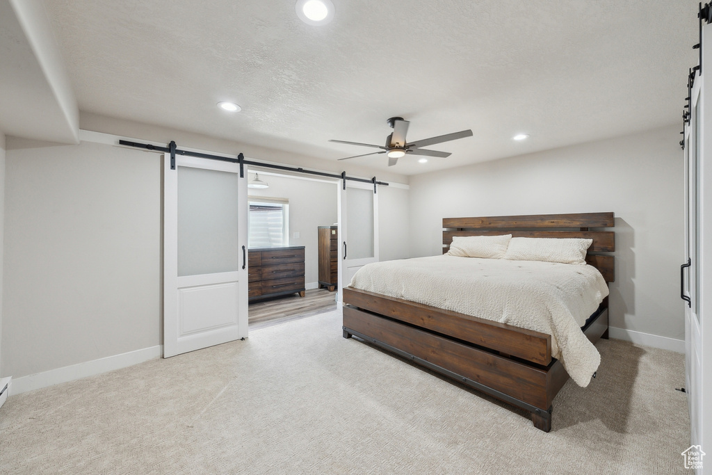 Bedroom with baseboards, a barn door, light carpet, and recessed lighting