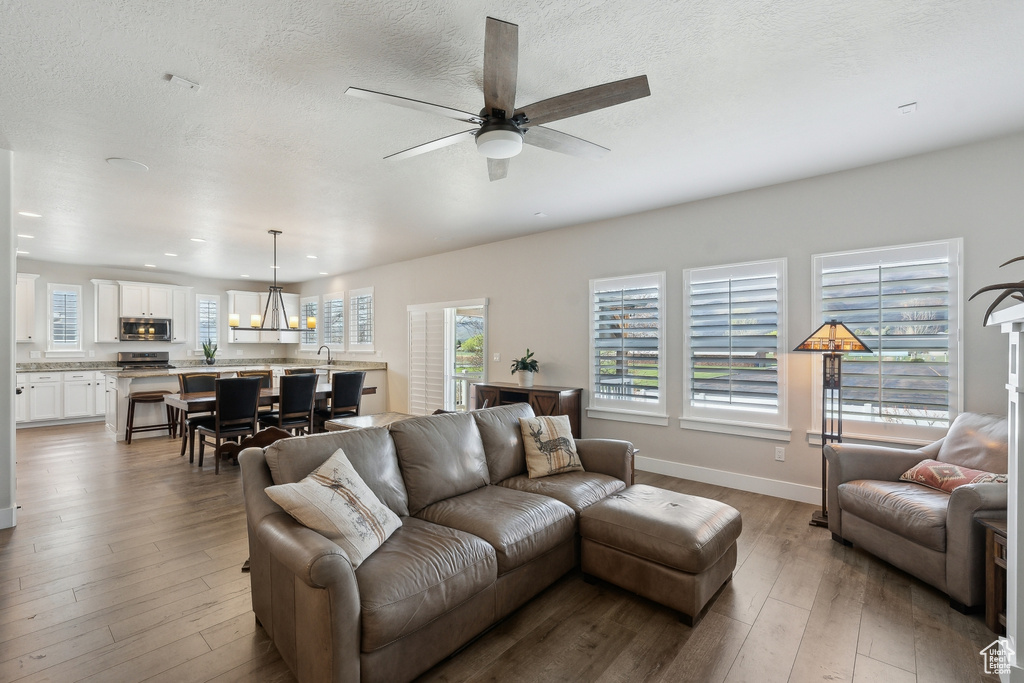 Living area with recessed lighting, a ceiling fan, hardwood / wood-style flooring, and baseboards