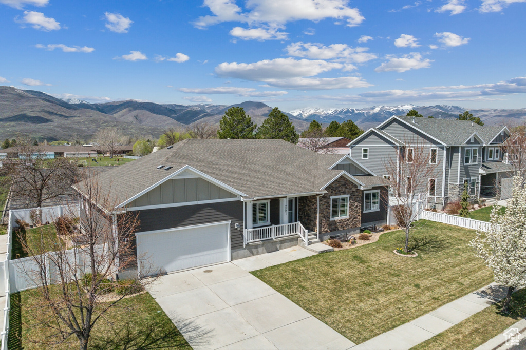 View of front of house with a front lawn, driveway, board and batten siding, and a mountain view