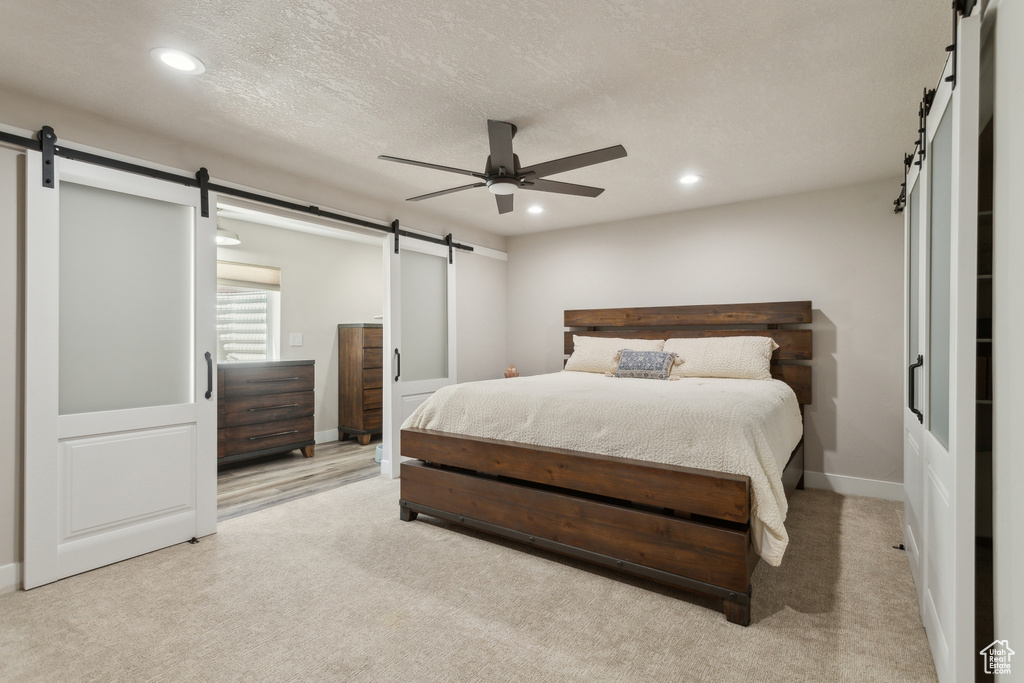 Bedroom featuring a barn door, recessed lighting, light colored carpet, a ceiling fan, and baseboards