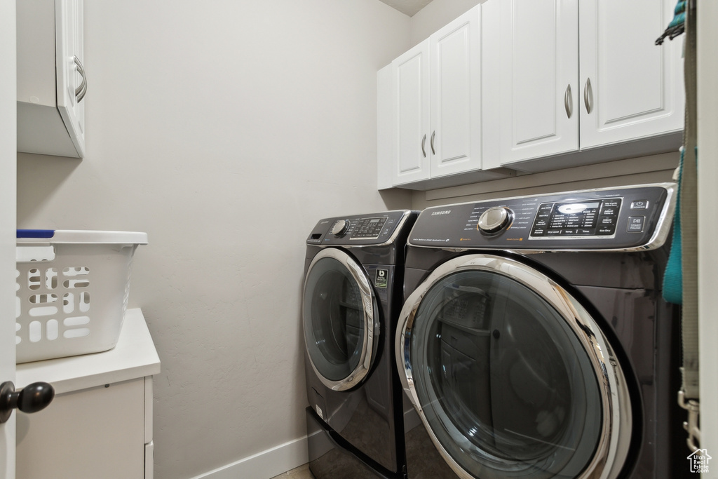 Laundry room featuring cabinet space, washing machine and clothes dryer, and baseboards