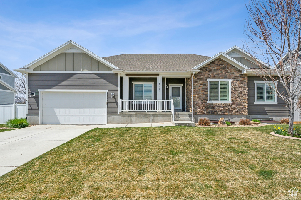 Craftsman-style home with a front yard, a garage, covered porch, driveway, and board and batten siding