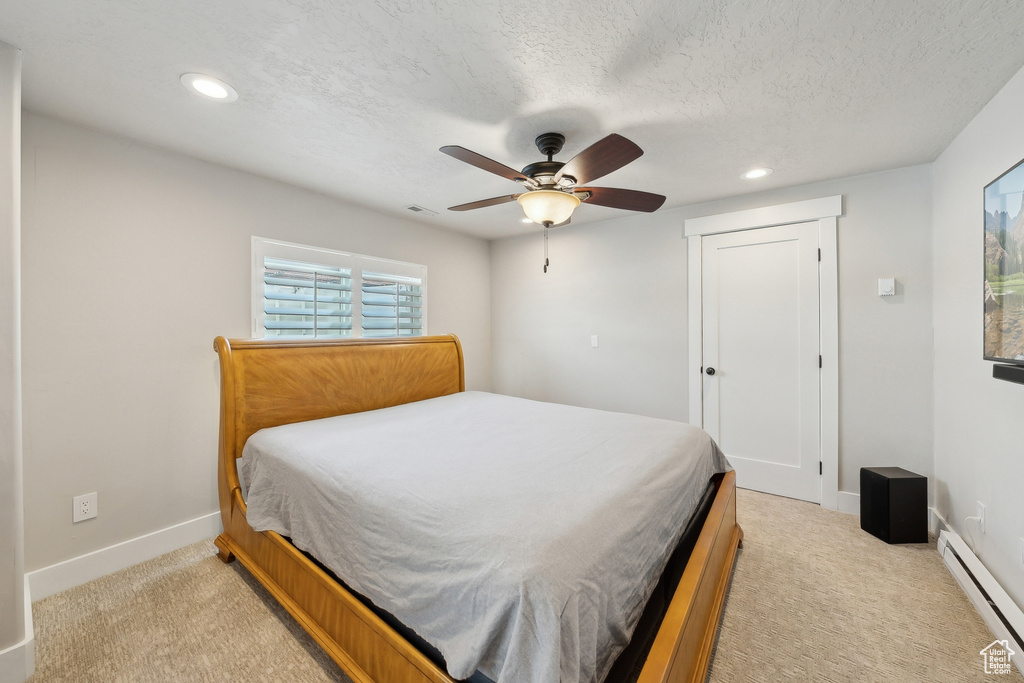 Bedroom featuring recessed lighting, a baseboard heating unit, light carpet, baseboards, and visible vents