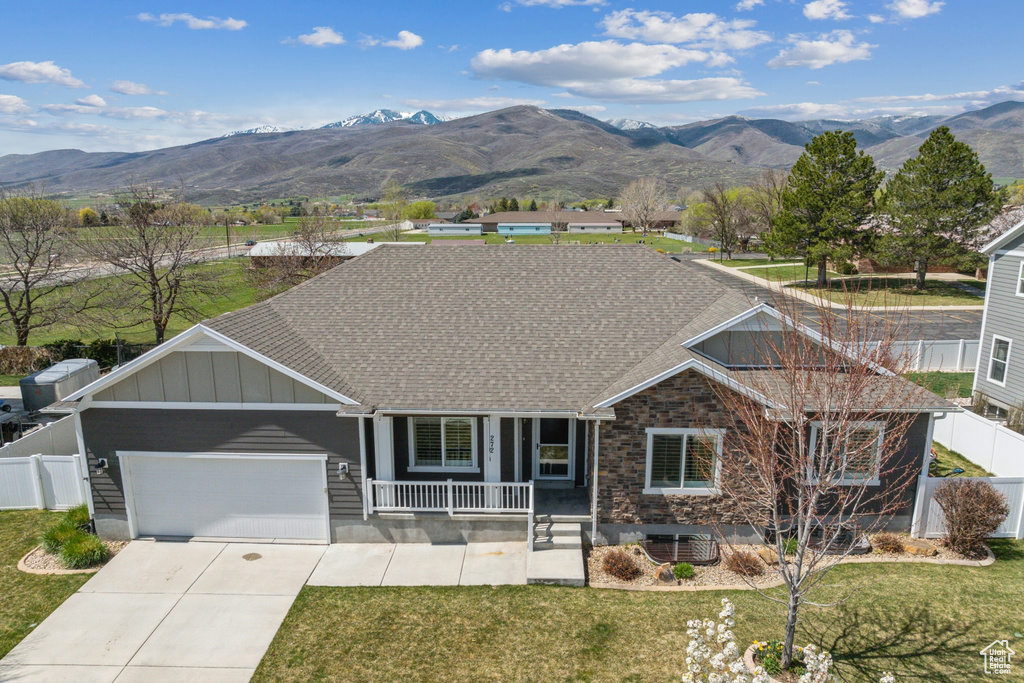 Ranch-style home with fence, covered porch, a mountain view, and an attached garage