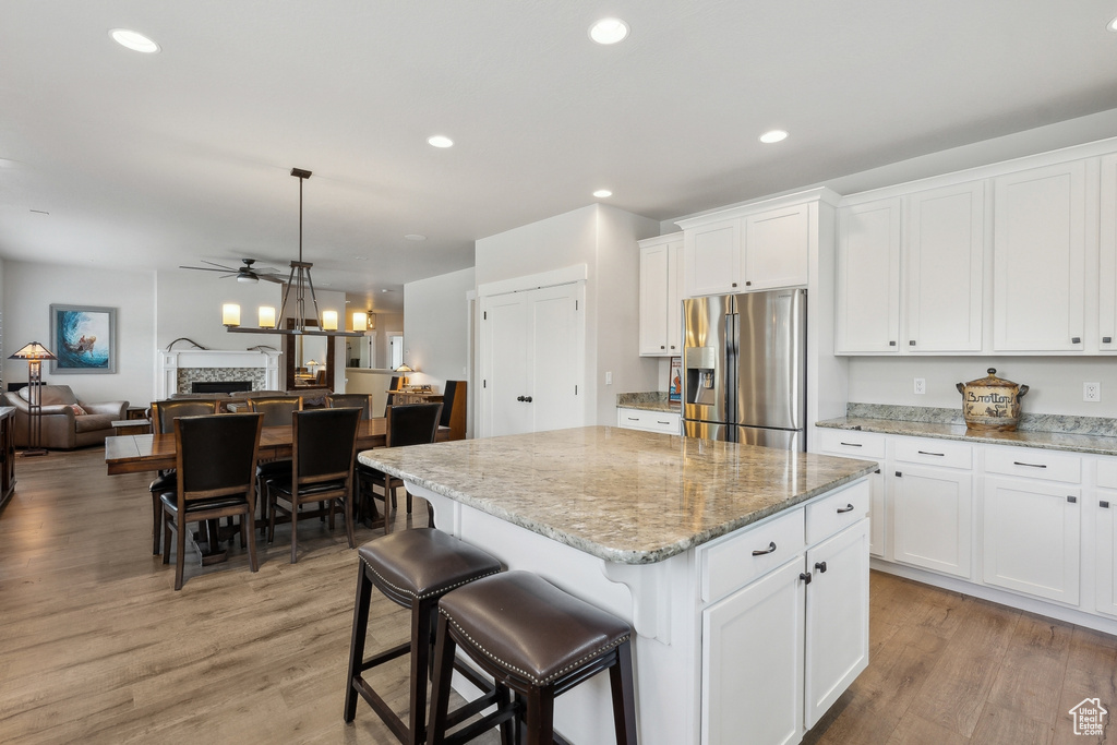 Kitchen featuring stainless steel refrigerator with ice dispenser, a ceiling fan, open floor plan, and light wood finished floors