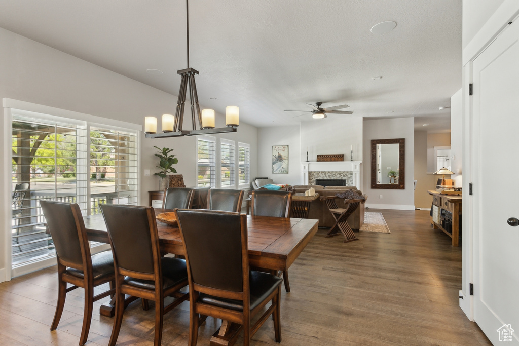 Dining area with a fireplace, ceiling fan, wood finished floors, and baseboards