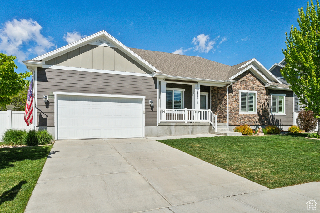 Craftsman-style house featuring covered porch, an attached garage, concrete driveway, board and batten siding, and stone siding