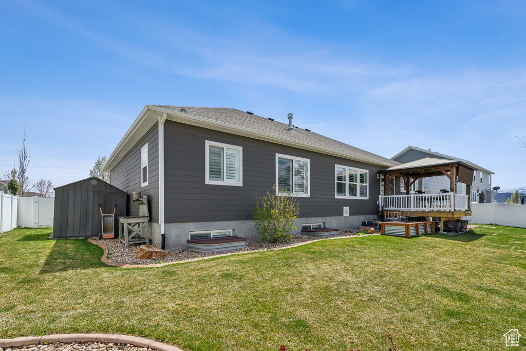 Rear view of house with a lawn, a storage shed, a gazebo, and a fenced backyard