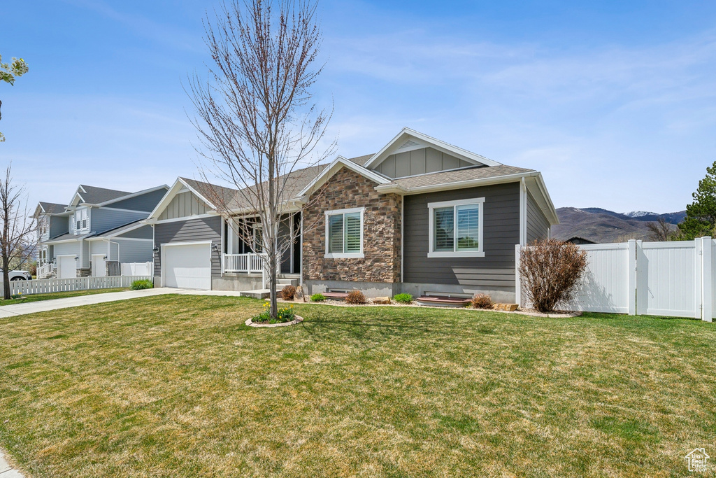 View of front of home with driveway, an attached garage, board and batten siding, and fence