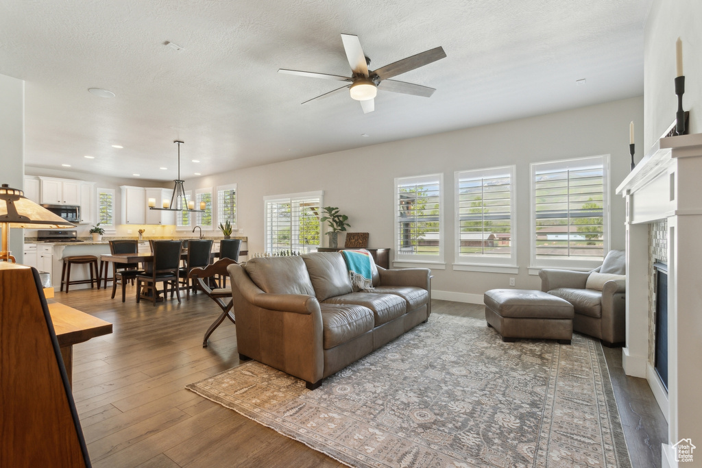Living area featuring a fireplace, a ceiling fan, wood finished floors, baseboards, and recessed lighting