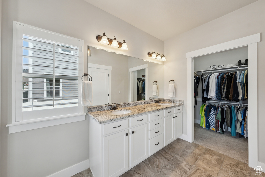 Full bath featuring a walk in closet, a healthy amount of sunlight, double vanity, and a sink
