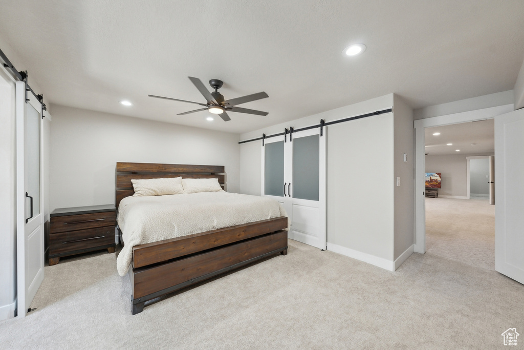 Bedroom with a barn door, recessed lighting, and light carpet