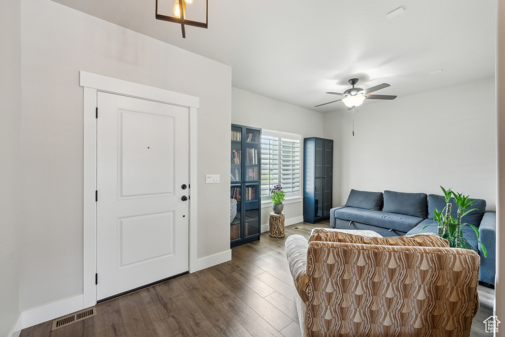 Living area with a ceiling fan, visible vents, wood finished floors, and baseboards