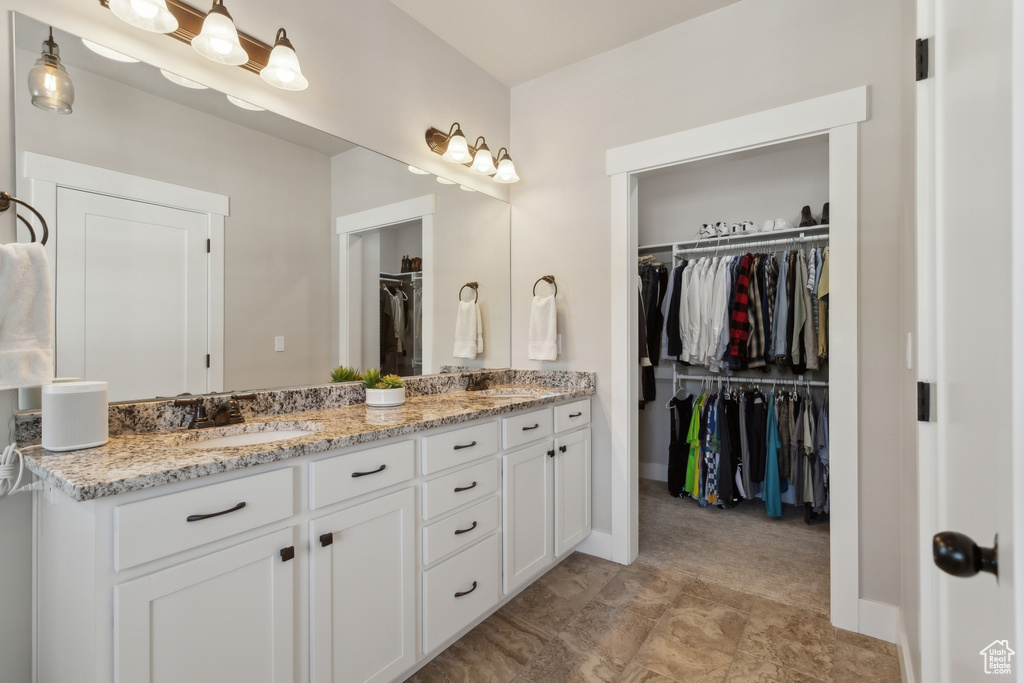 Bathroom featuring double vanity, a spacious closet, and baseboards