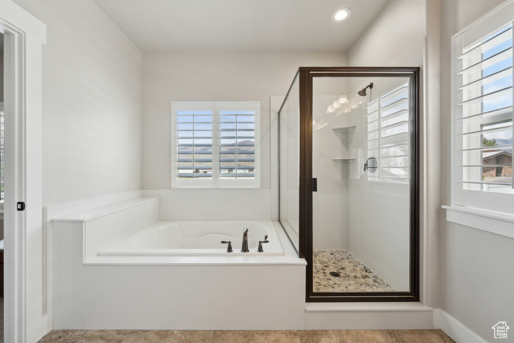 Full bath featuring a stall shower, a wealth of natural light, and a garden tub