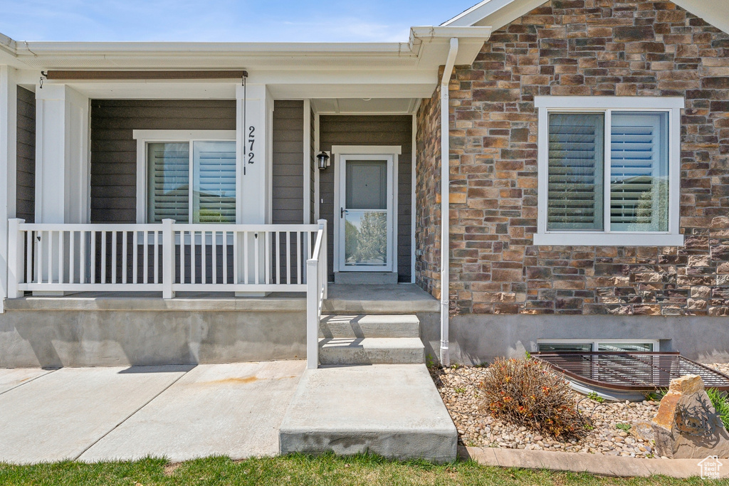 Entrance to property featuring covered porch and brick siding