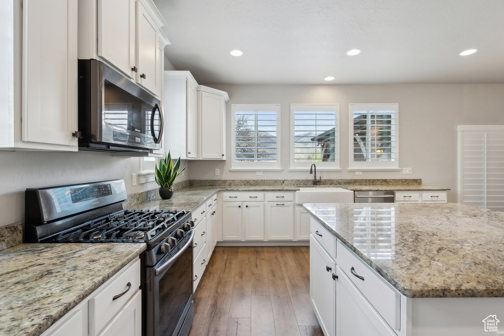 Kitchen with a sink, appliances with stainless steel finishes, a wealth of natural light, and white cabinetry