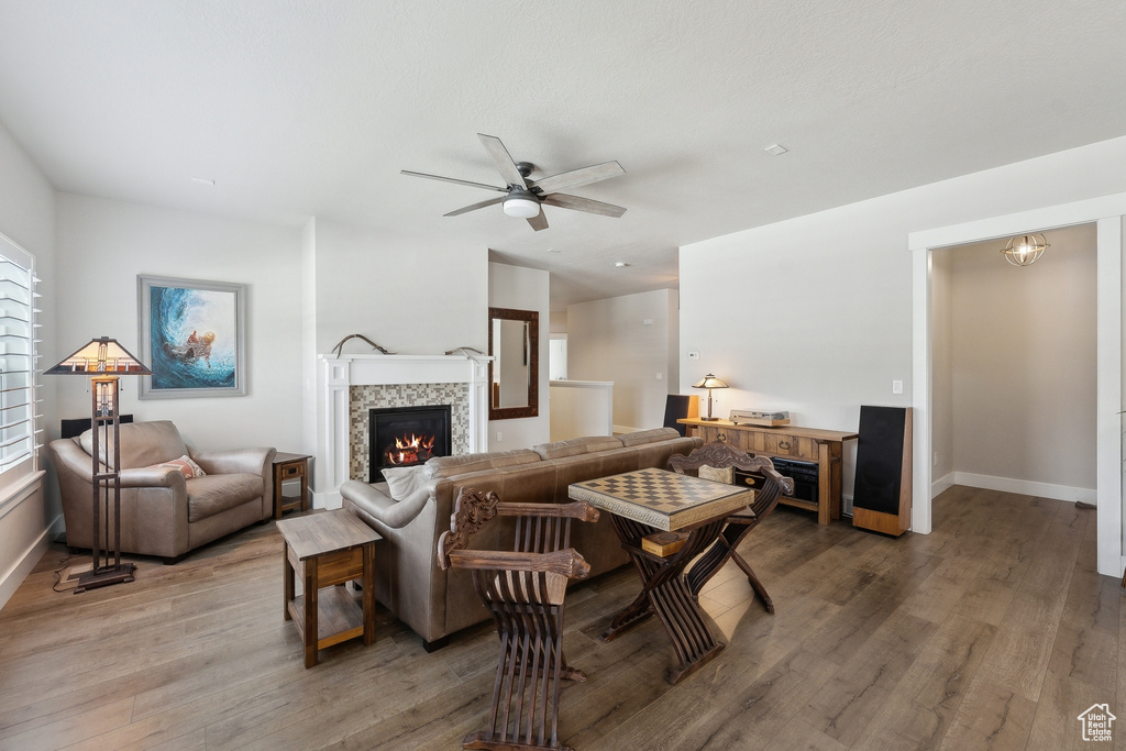 Living area featuring a tile fireplace, ceiling fan, light wood-type flooring, and baseboards