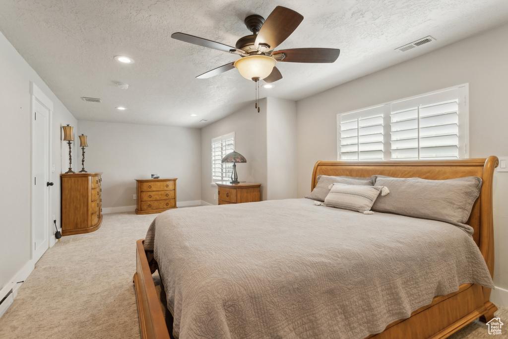 Carpeted bedroom with a textured ceiling, recessed lighting, baseboards, a ceiling fan, and a baseboard radiator