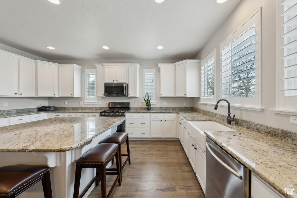 Kitchen featuring a breakfast bar area, a sink, appliances with stainless steel finishes, and a healthy amount of sunlight