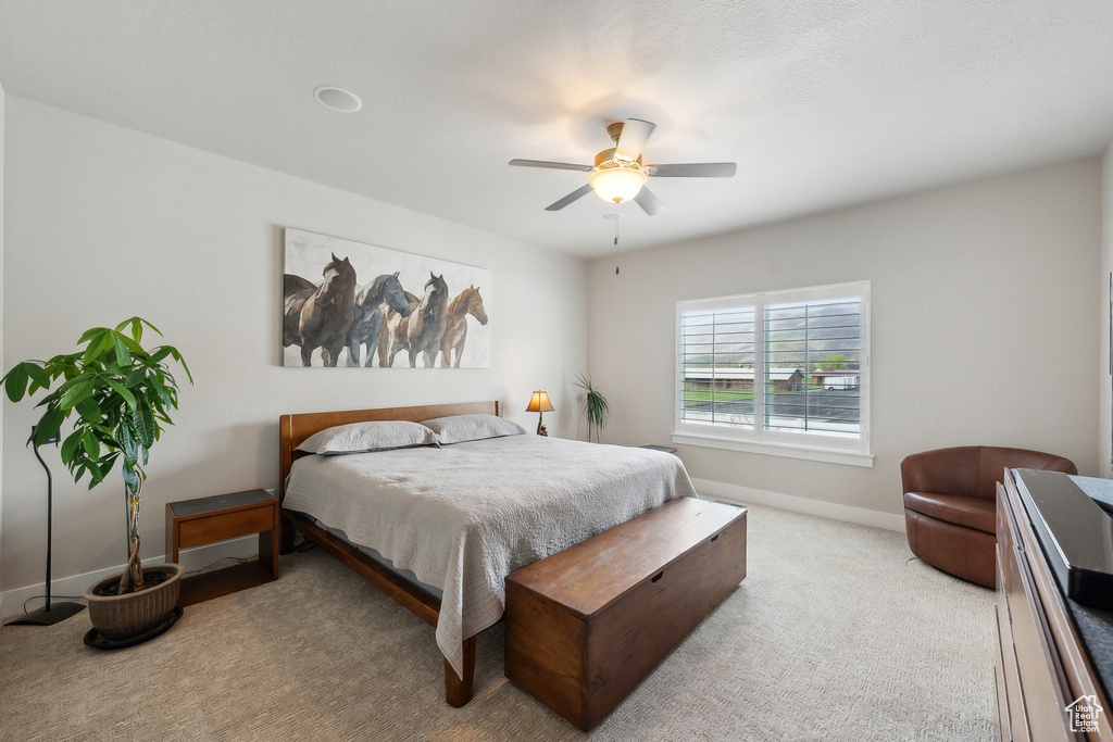 Bedroom with ceiling fan, light colored carpet, and baseboards