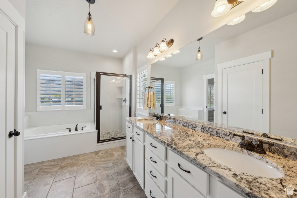 Bathroom featuring a bath, double vanity, a sink, and a shower stall