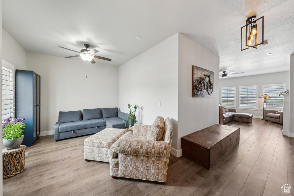 Living area with a ceiling fan, wood finished floors, and baseboards