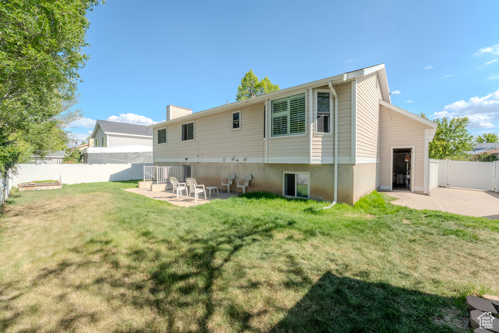 Back of property featuring a lawn, a patio, fence, and a chimney