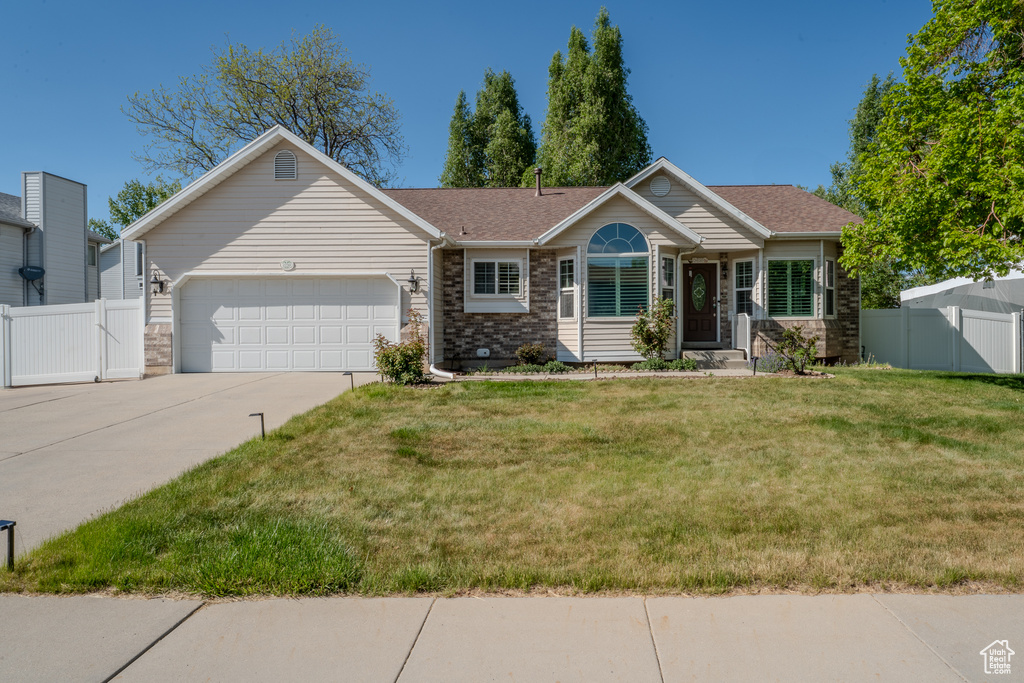 Single story home with driveway, a front yard, a gate, a garage, and fence