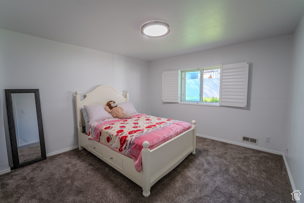 Bedroom with visible vents, baseboards, and dark colored carpet
