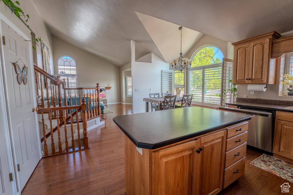 Kitchen featuring dark wood-style flooring, dark countertops, lofted ceiling, and dishwasher