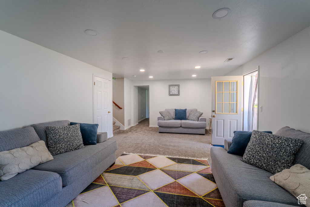 Living room with stairs, recessed lighting, baseboards, and light carpet