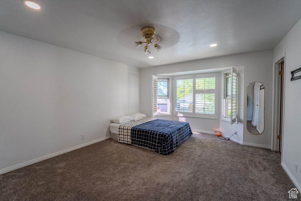 Carpeted bedroom featuring baseboards, ceiling fan, and recessed lighting