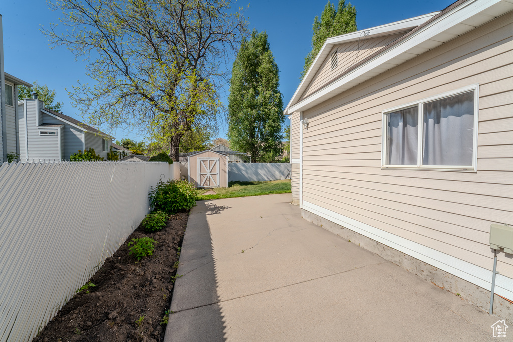 View of home's exterior with a fenced backyard, an outdoor structure, a patio area, and a shed