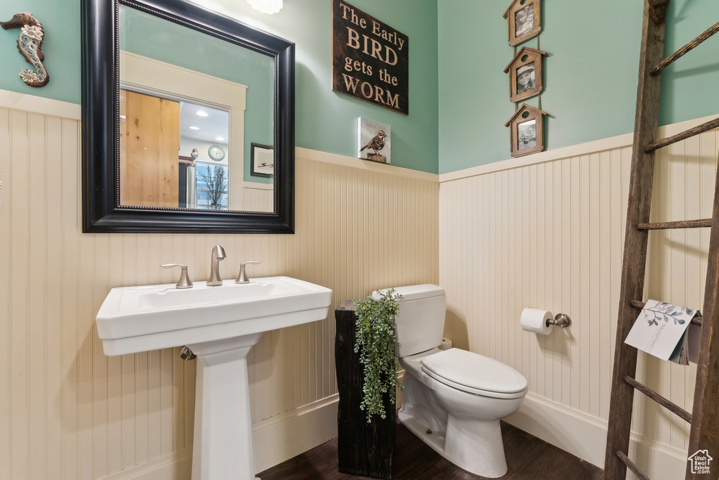 Bathroom featuring toilet, wainscoting, and wood finished floors