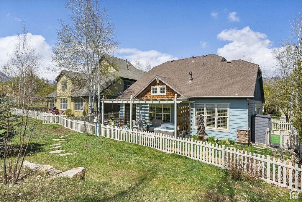 Back of property featuring a yard, a fenced backyard, roof with shingles, and a patio area