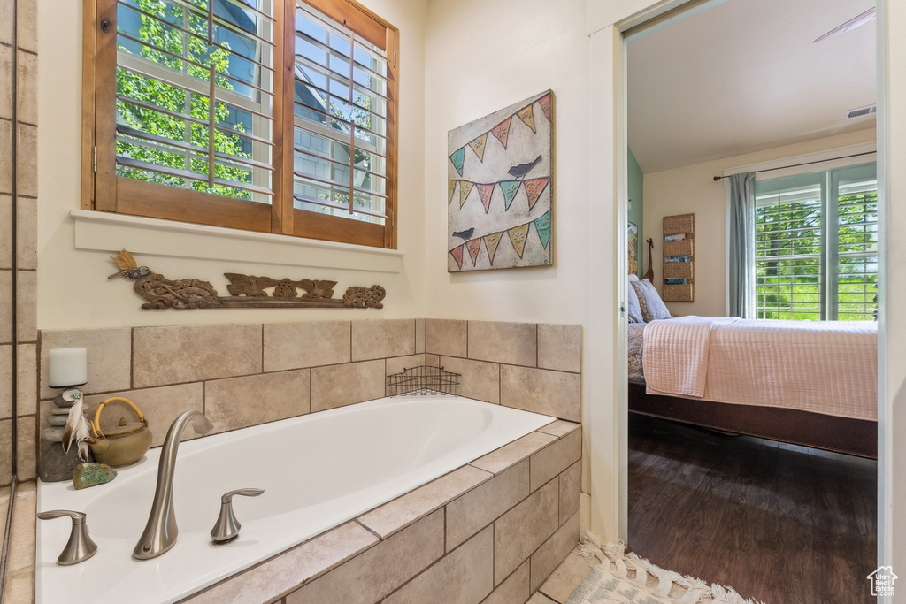 Full bath featuring ensuite bathroom, a garden tub, and wood finished floors