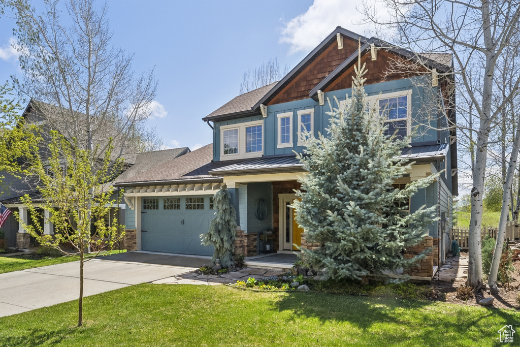 Craftsman house with covered porch, roof with shingles, a front yard, concrete driveway, and an attached garage