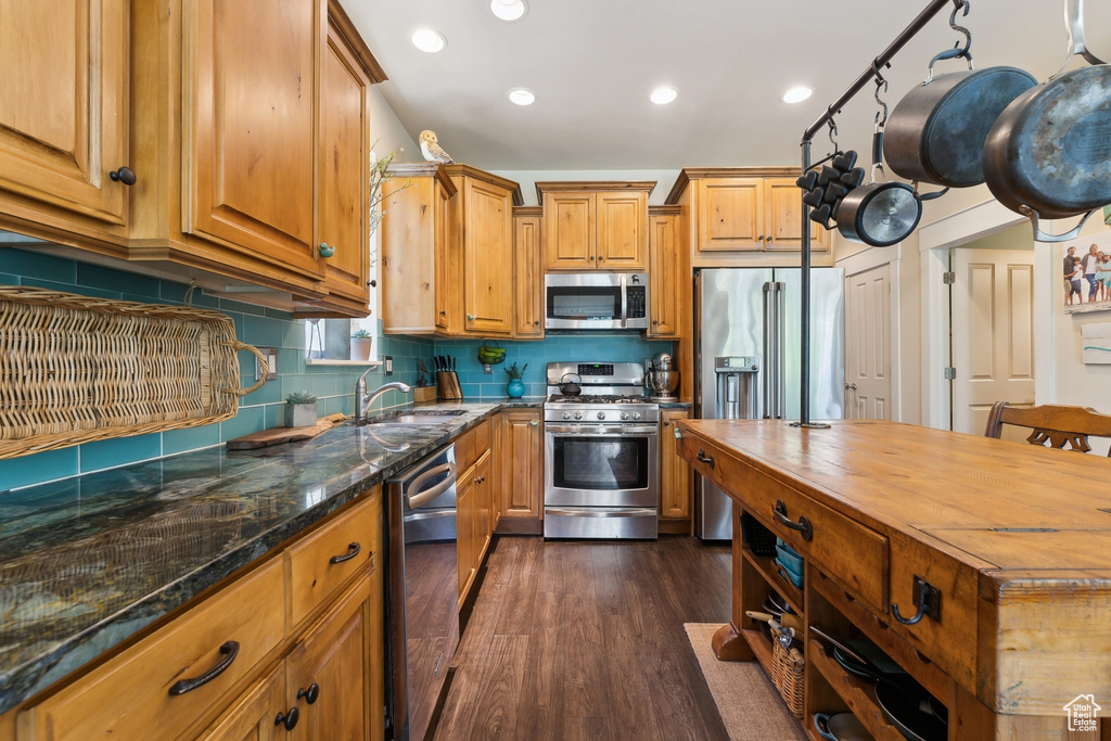 Kitchen featuring stainless steel appliances, a sink, butcher block countertops, dark wood-style flooring, and backsplash