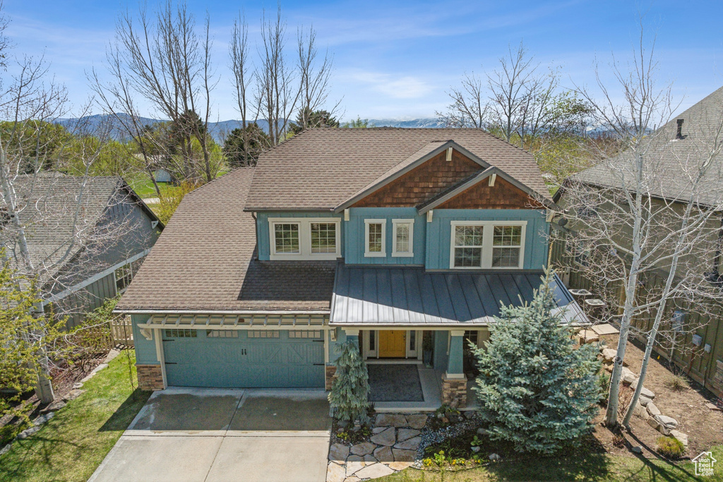 Craftsman-style house with a garage, a shingled roof, metal roof, a porch, and driveway
