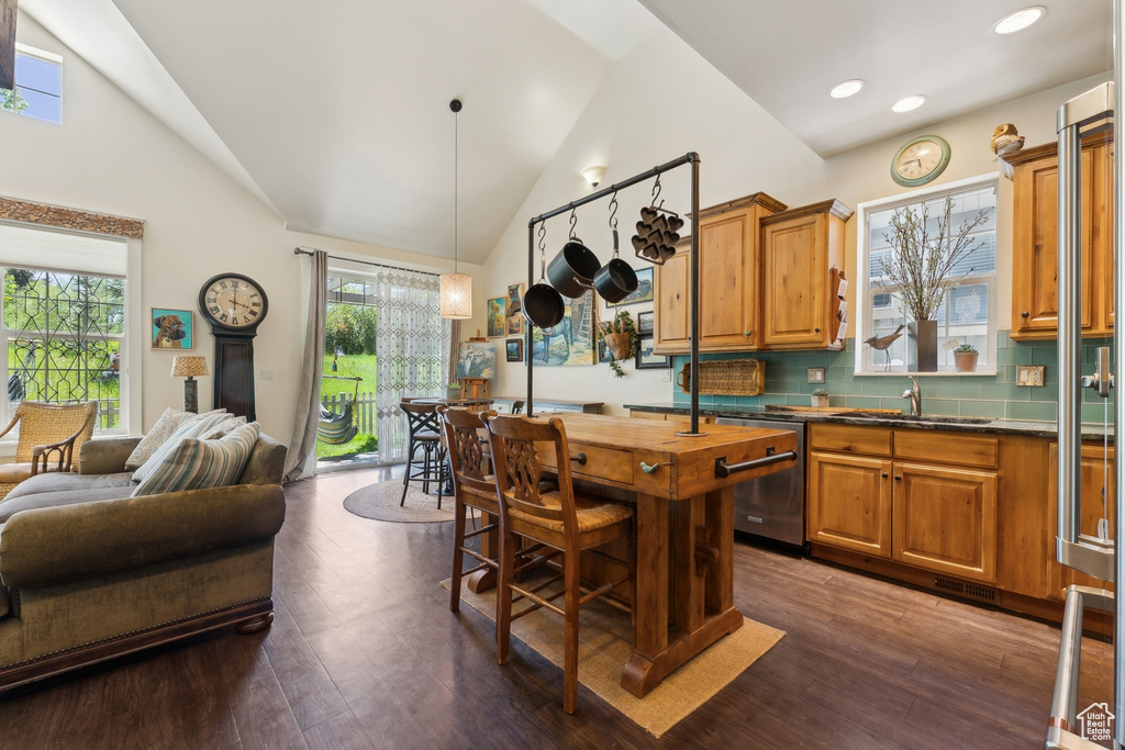 Kitchen with a sink, dishwasher, dark countertops, brown cabinetry, and open floor plan