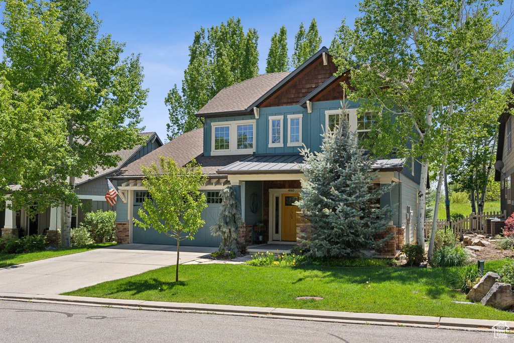 Craftsman house with concrete driveway, a front yard, roof with shingles, and a standing seam roof
