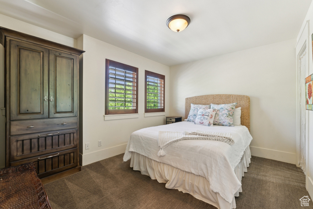 Bedroom featuring baseboards and dark carpet