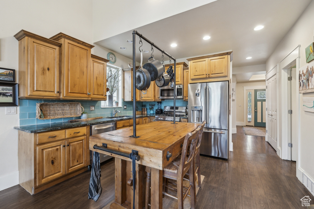 Kitchen with appliances with stainless steel finishes, a sink, recessed lighting, backsplash, and dark wood-style floors