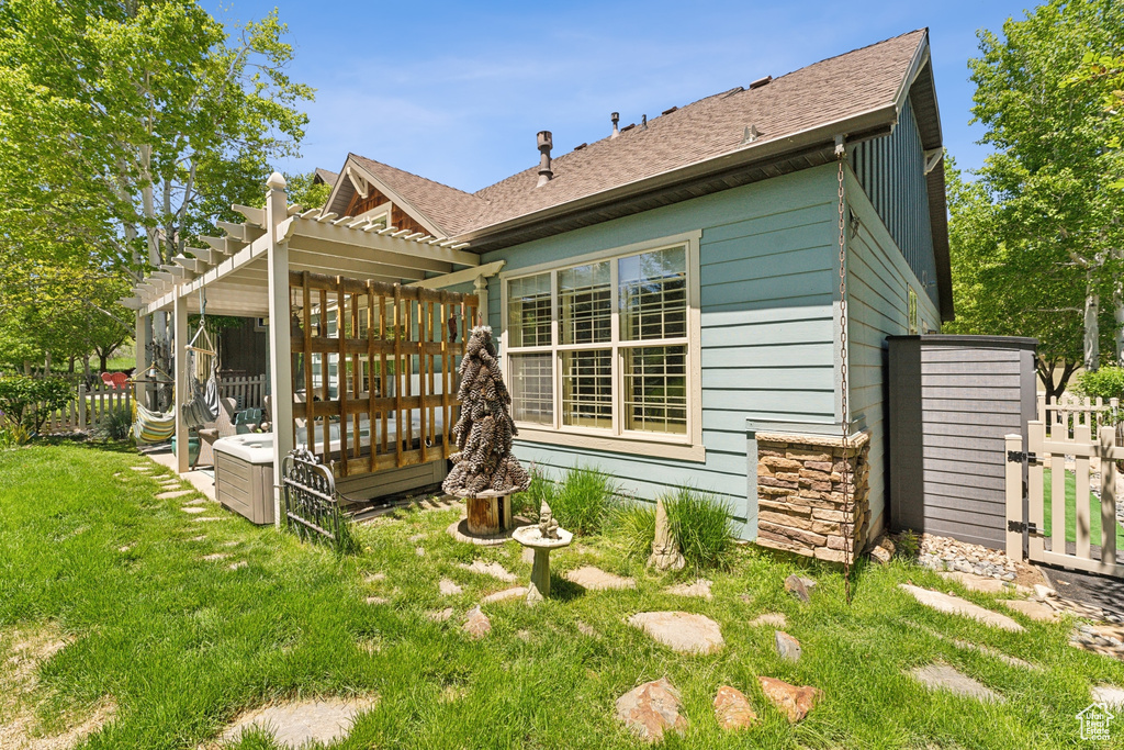 Rear view of house with a pergola, a wooden deck, roof with shingles, and stone siding