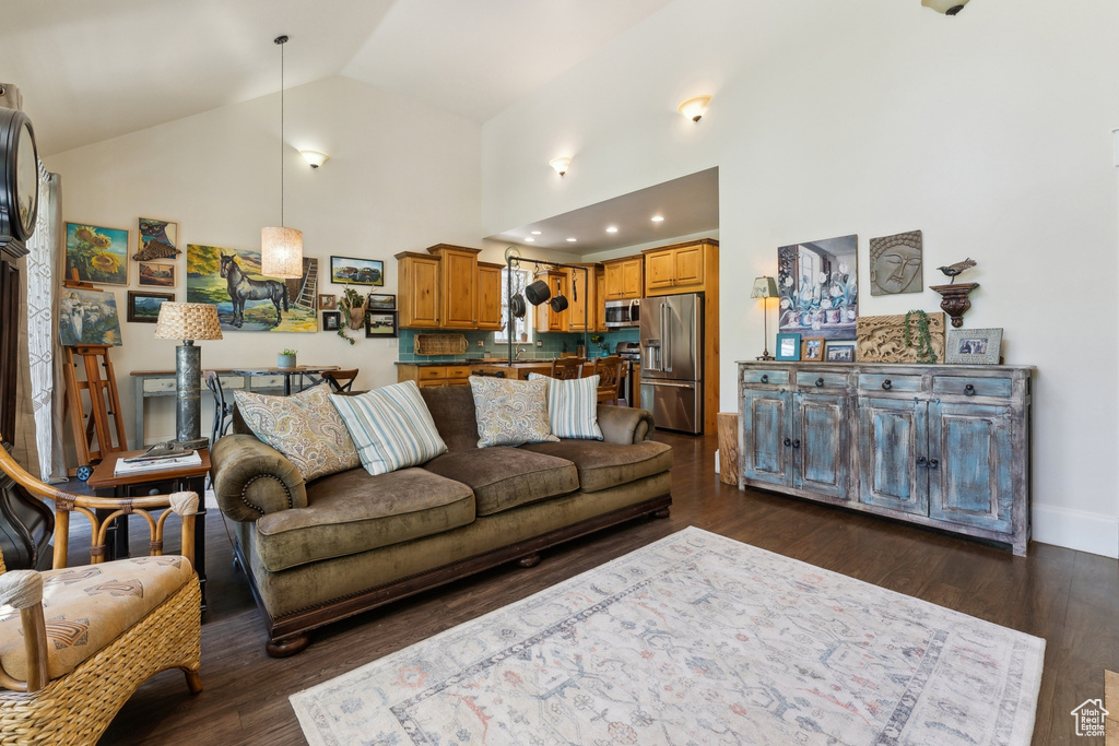 Living room featuring dark wood-style floors, high vaulted ceiling, and baseboards