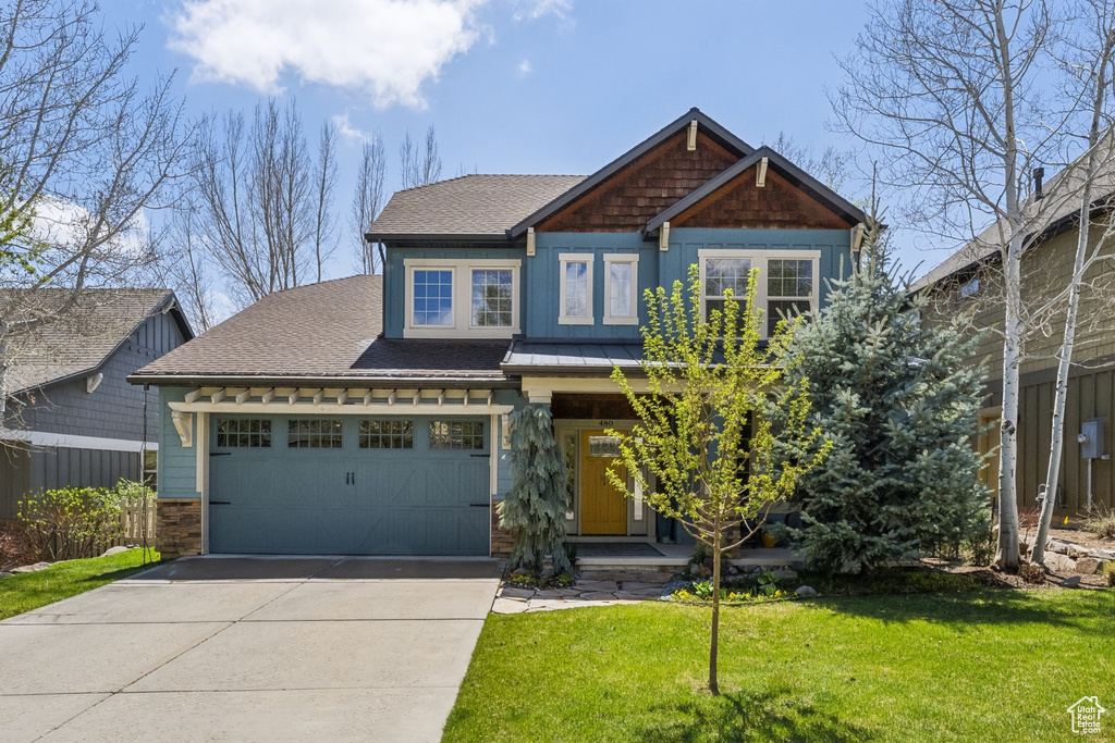 Craftsman inspired home featuring a garage, roof with shingles, driveway, and a front yard