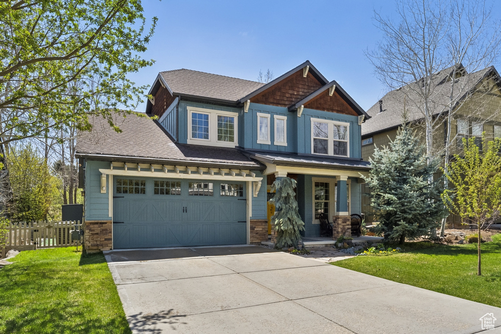Craftsman inspired home featuring a garage, a front lawn, fence, covered porch, and driveway