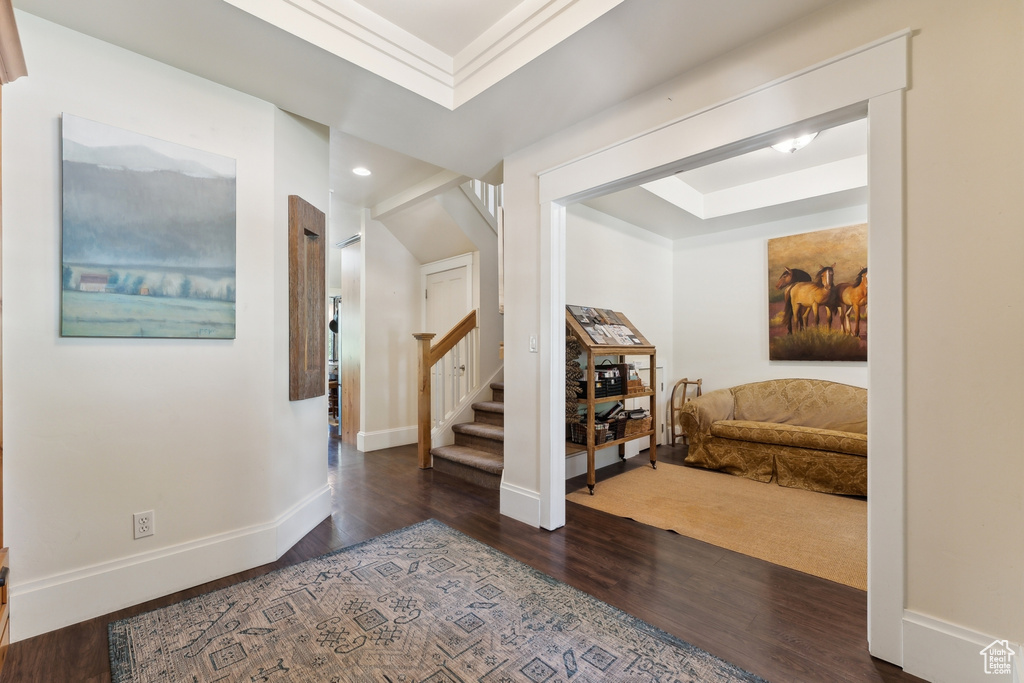 Corridor featuring a raised ceiling, wood finished floors, stairway, baseboards, and recessed lighting